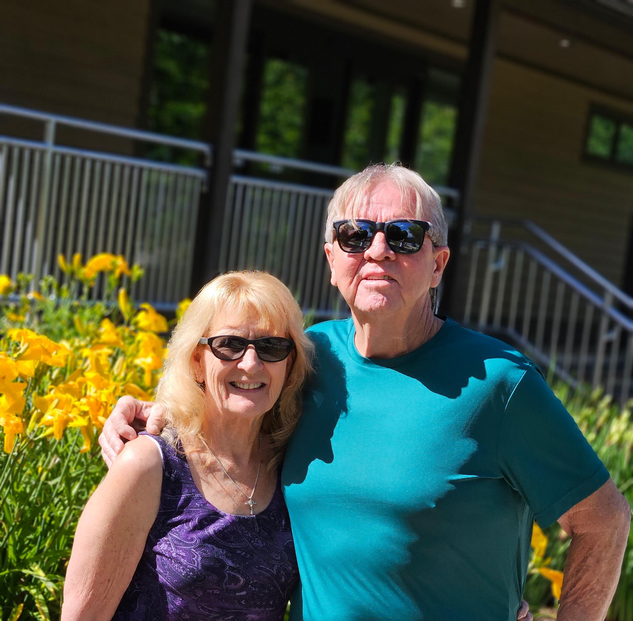 Rick and Terri outdoors by yellow flowers